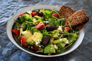 Griechischer Salat mit Avocado, Feta, Oliven und Brot